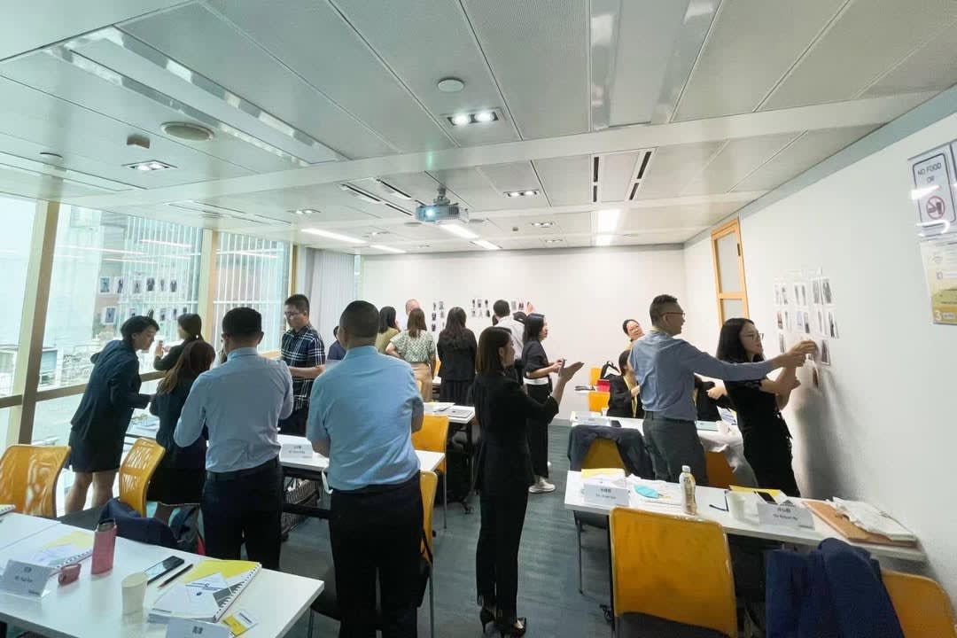 Participants actively engaged in a training session, standing and interacting with materials on a wall.