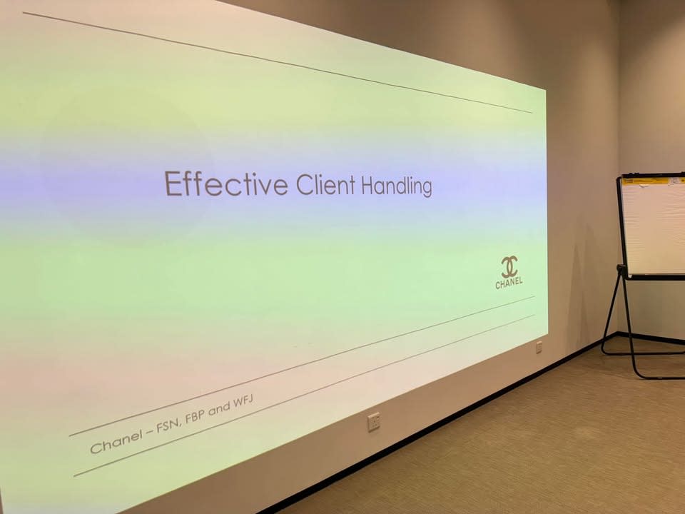 A projector screen displays a presentation slide titled 'Effective Client Handling' with the Chanel logo.